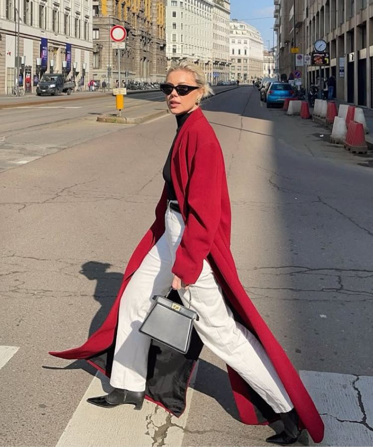 A woman modeling a bright red wool coat against a neutral background.