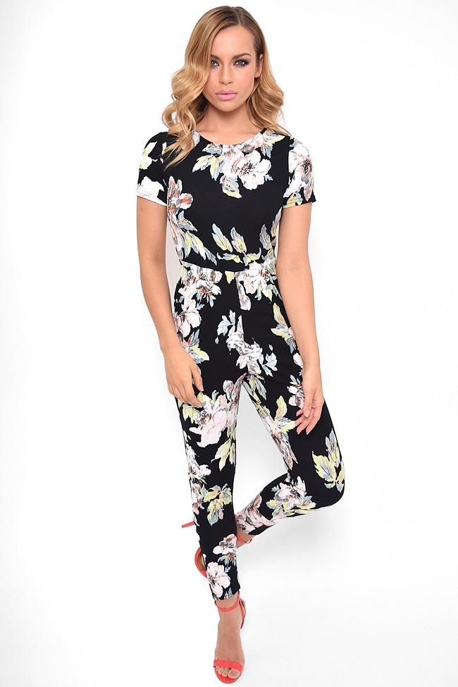 Full-length shot of a black floral jumpsuit styled with vibrant coral high heels.