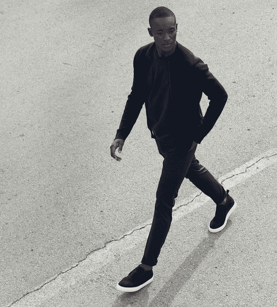 Minimalist white sneakers styled with tailored grey trousers and a monochrome knit.
