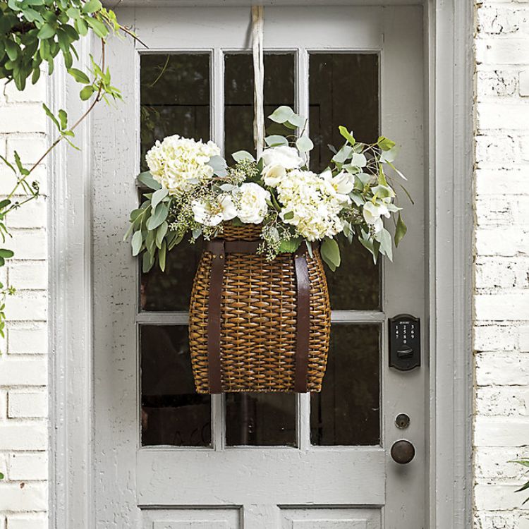 A hanging woven basket on a front door for a welcoming entryway.