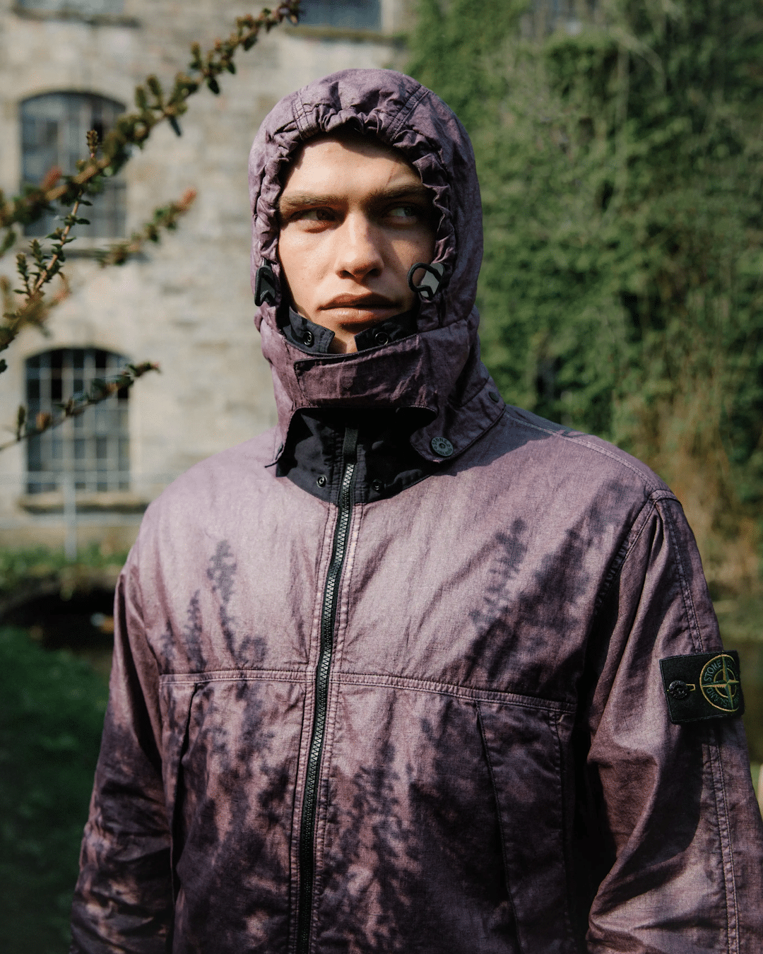 Close-up of a purple tie-dye Stone Island hooded jacket with a visible compass logo patch.