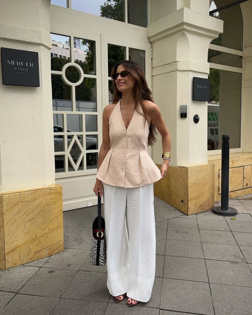 Full body shot of a woman in a fitted top and wide leg trousers.