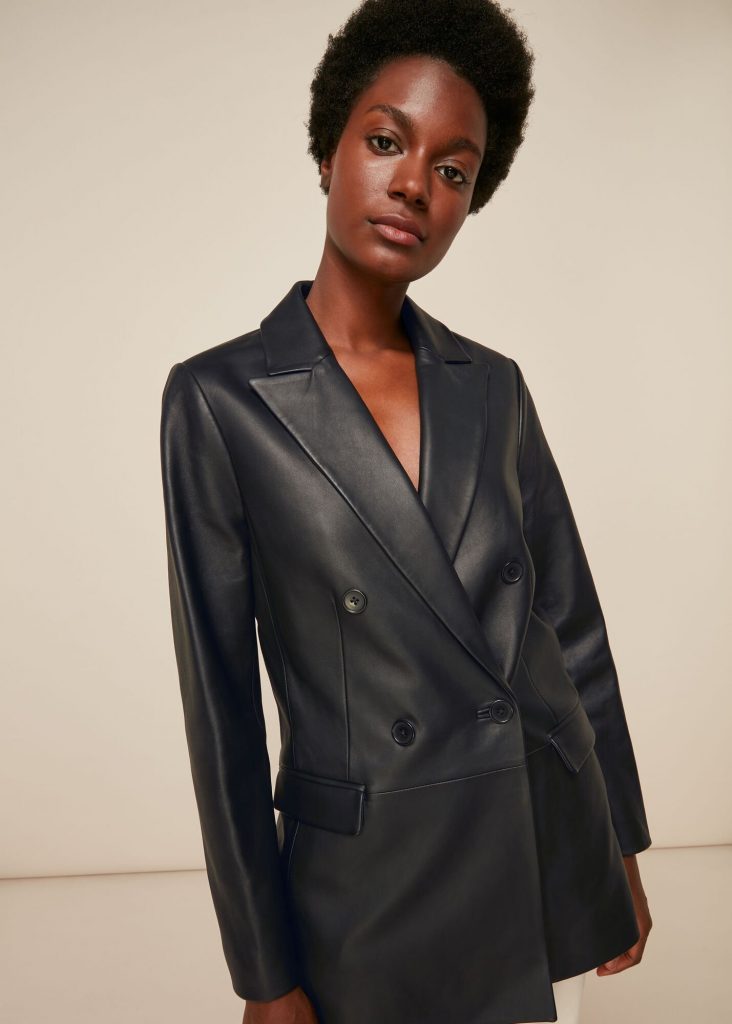Woman in a black double-breasted leather blazer with structured shoulders.