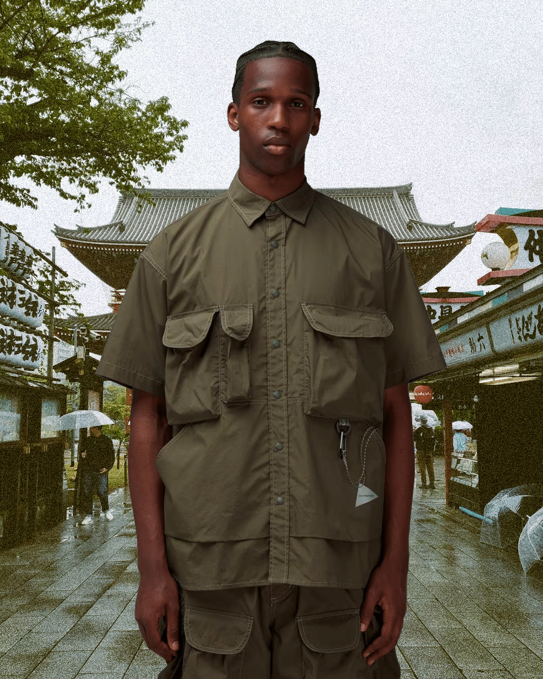 Man in an olive green utility shirt and matching cargo pants in a traditional Japanese setting.