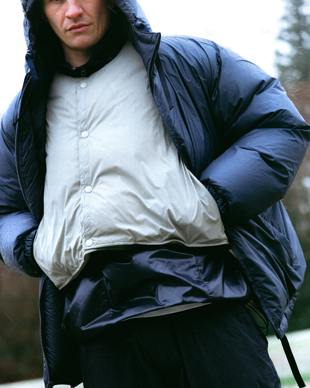 Side profile of a parka showing functional utilitarian pockets and reinforced panels.