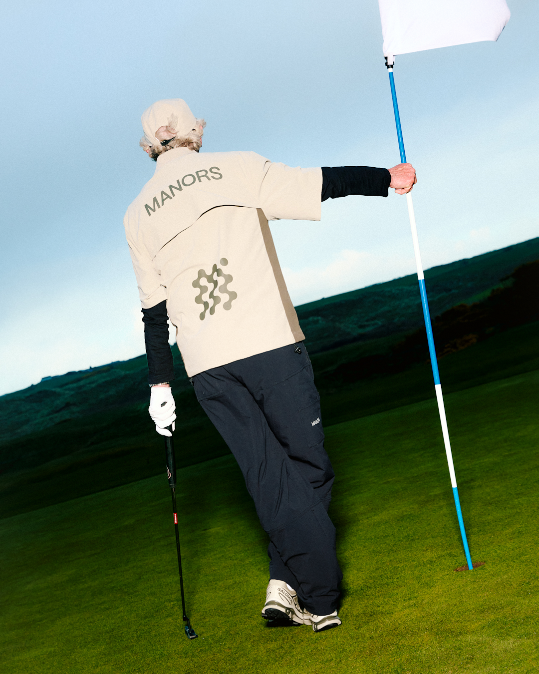 Close-up of a Malbon Golf jacket featuring a custom camouflage pattern and the brand's signature script logo.