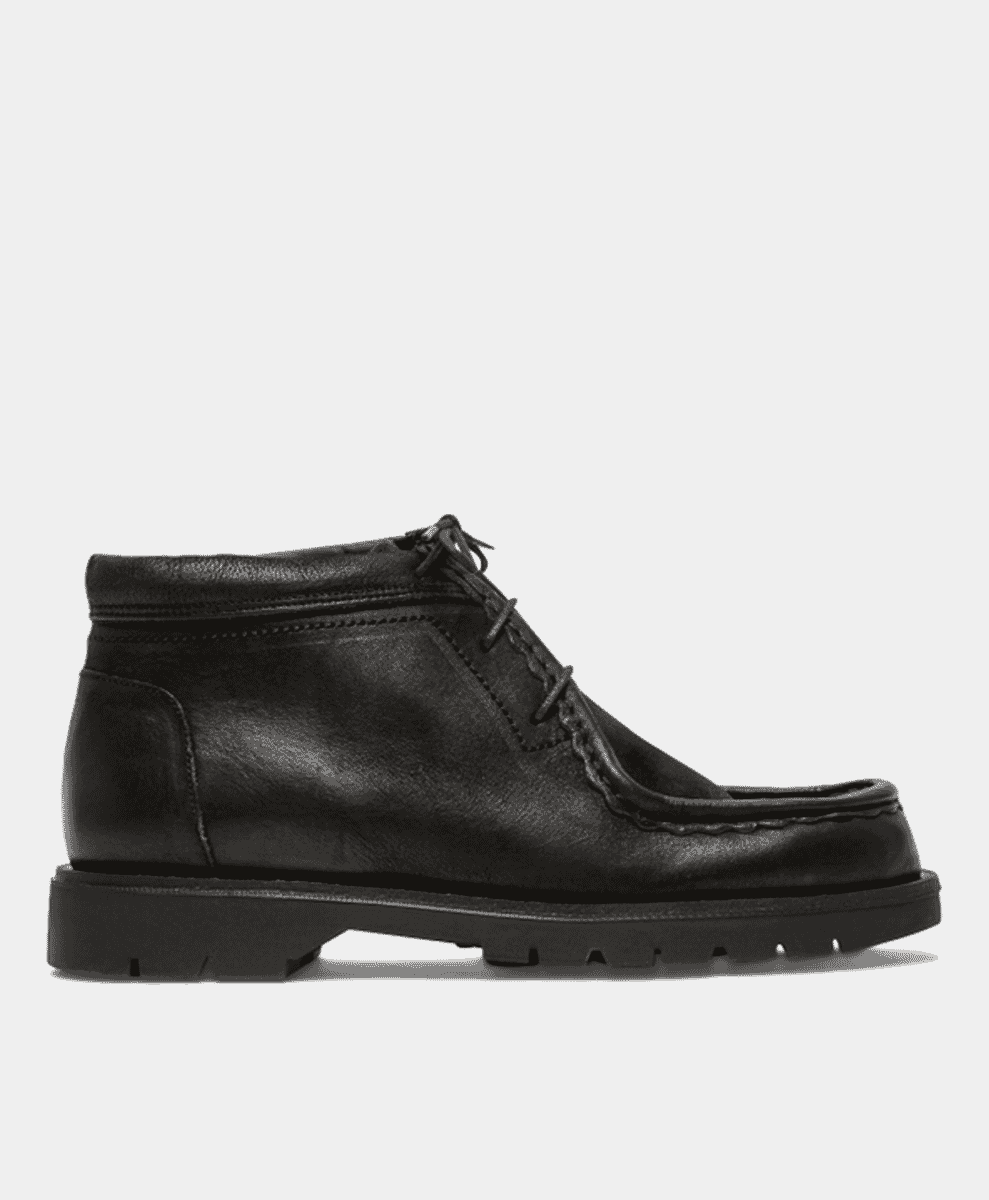 Side view of a black leather Chelsea boot with a chunky tread sole against a white background.