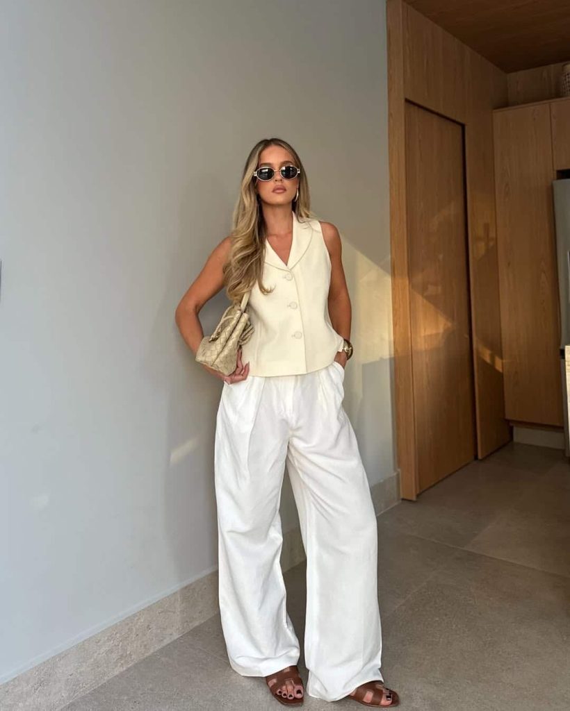 A woman wearing wide leg trousers with a belt to emphasize the waistline.