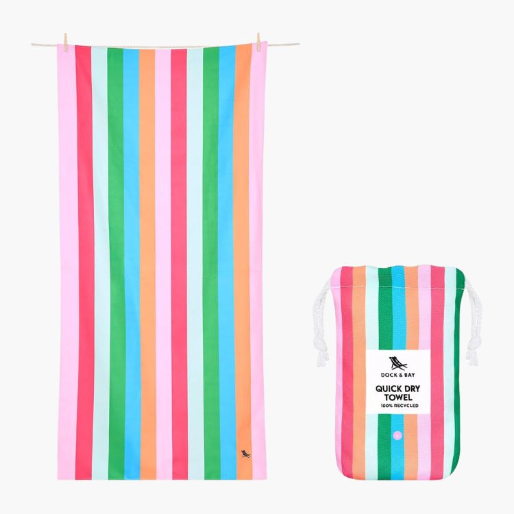 A colorful striped Dock & Bay quick-dry towel hanging next to its storage pouch.