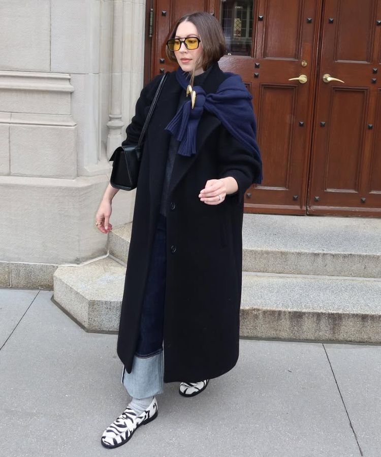 Full-length street style shot of a woman in a tailored black wool coat and leggings.
