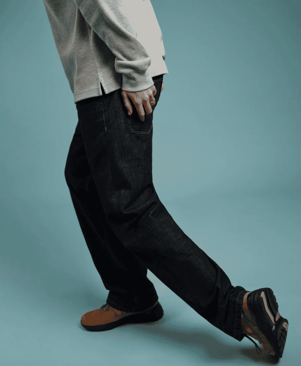 A man styling straight jeans with a textured navy knit sweater.