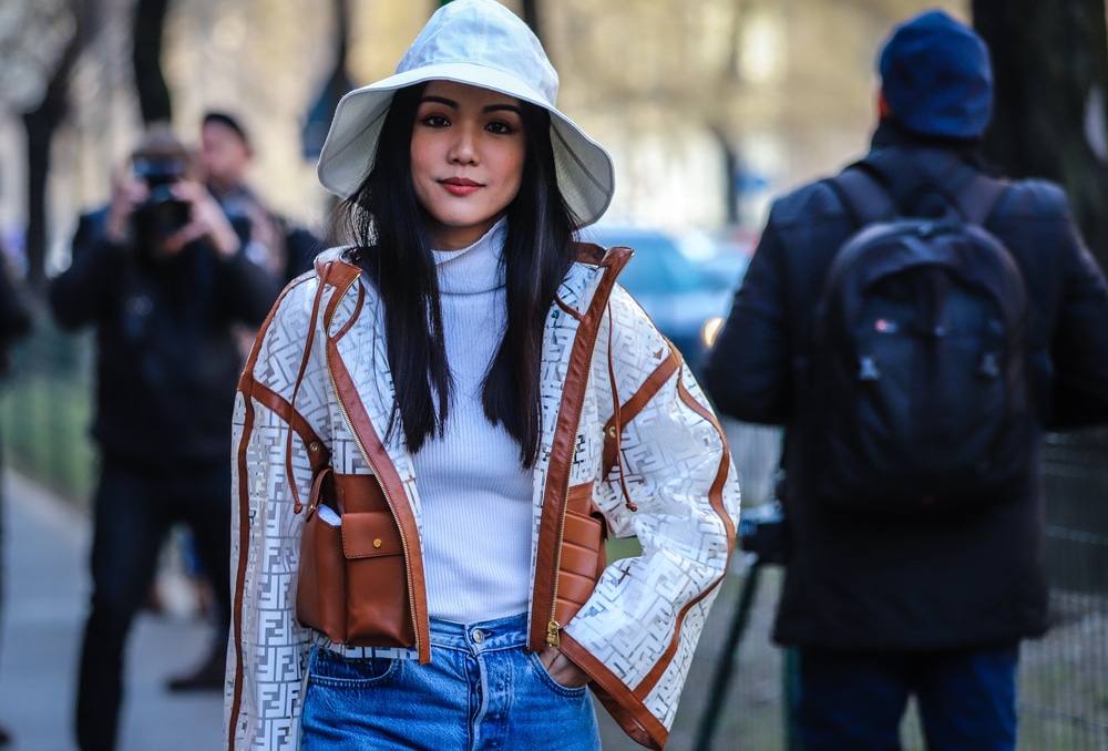 A woman in a Fendi jacket and blue jeans, representing a mix of luxury and approachable style.