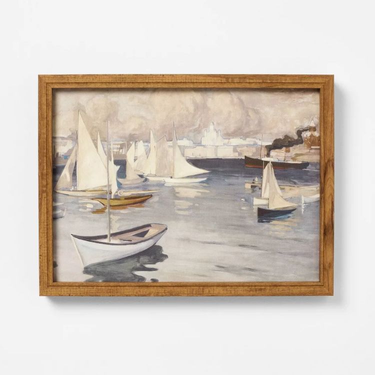 Framed wall art featuring coastal boat imagery in a thin frame.