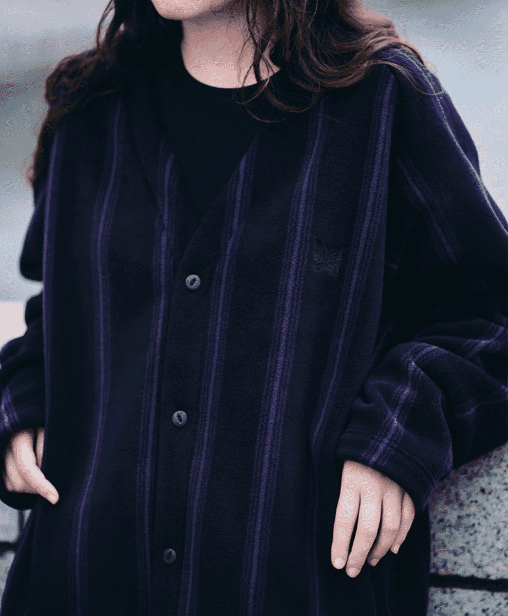 Close-up of a dark navy fleece cardigan with vertical purple stripes and button closures.