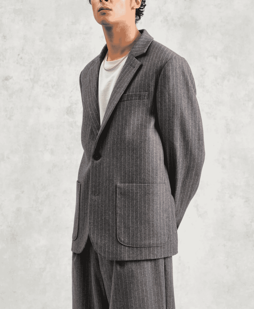 Man modeling a charcoal grey pinstripe wool blazer in a relaxed fit.