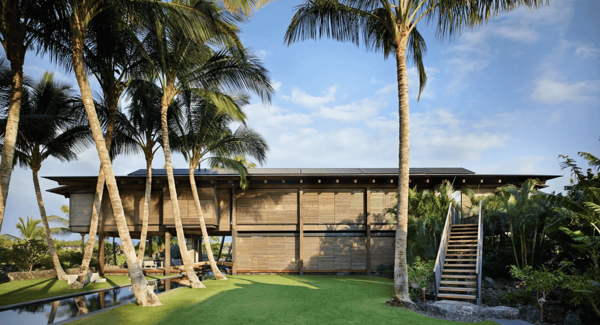 Close-up of a modern residence with vertical wooden slats and palm trees.