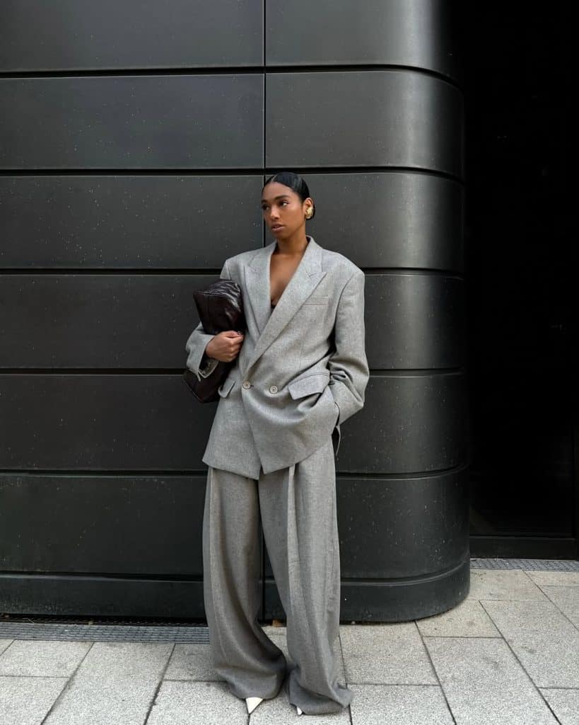 A woman wearing a full oversized grey wool suit with wide-leg trousers.