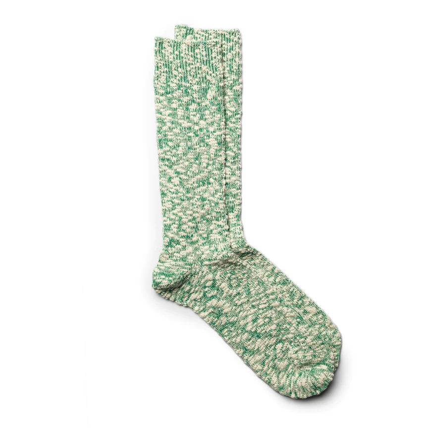 A green and cream marled knit sock showcasing a speckled, earthy texture.