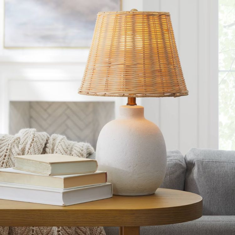 Ceramic table lamp with a natural rattan shade on a side table.
