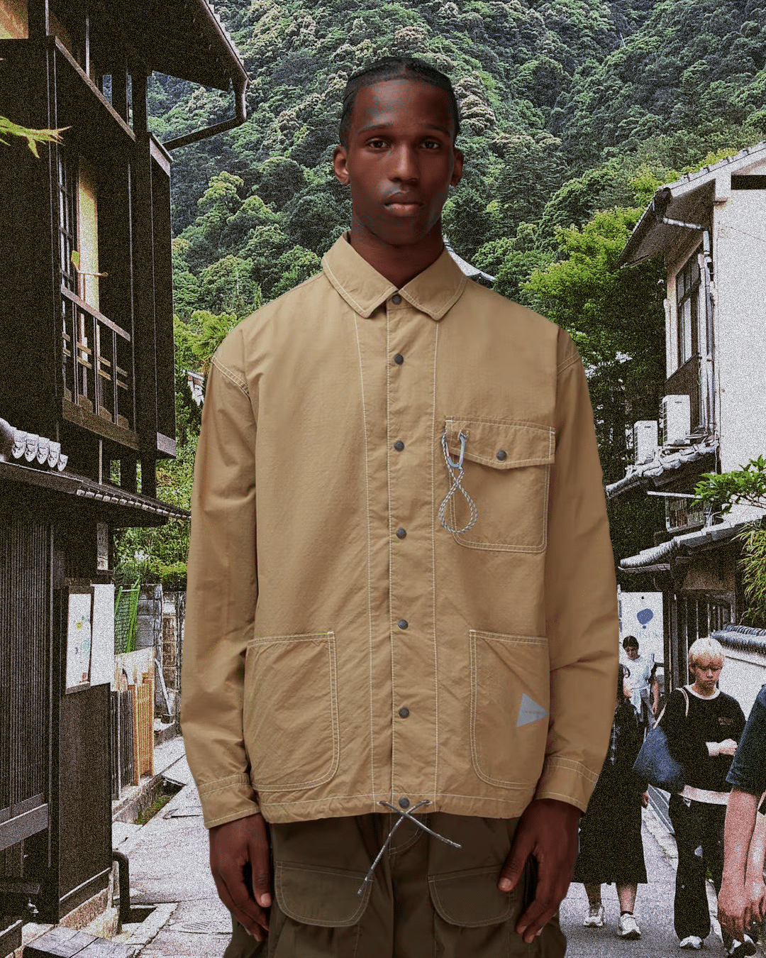 Man in a beige utility jacket and olive cargo pants against a Japanese scenery collage.