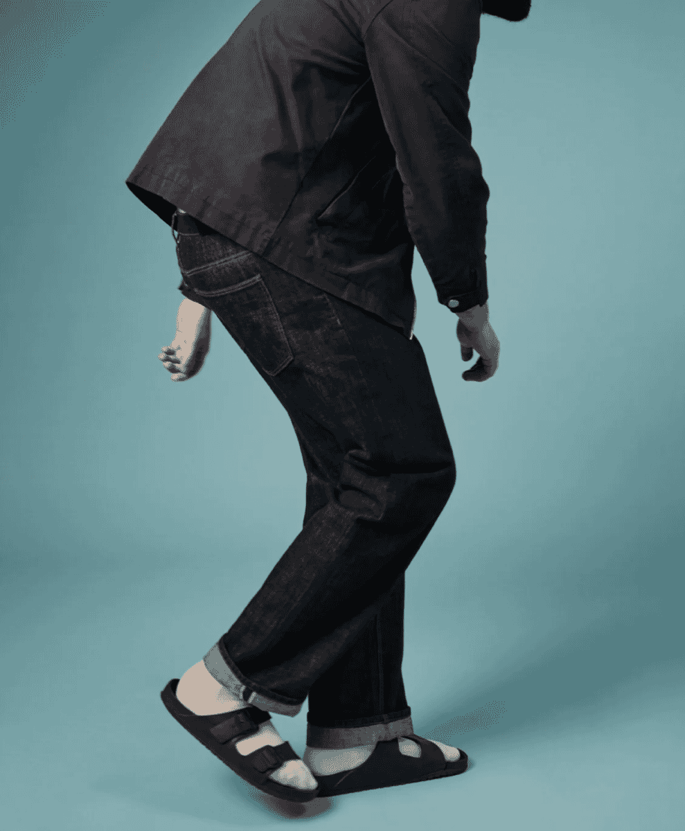 A man leaning against a railing wearing straight-leg jeans in a lifestyle context.