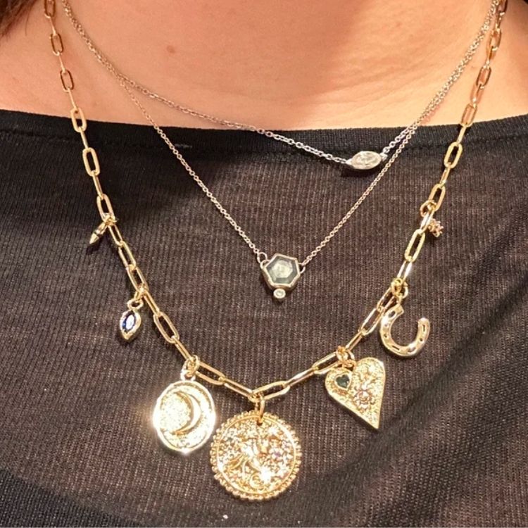 Custom gold charm necklace with multiple initial charms.