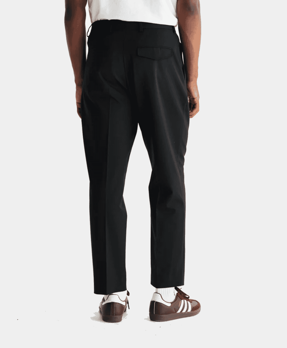 Rear view of a man wearing black pleated wool trousers.